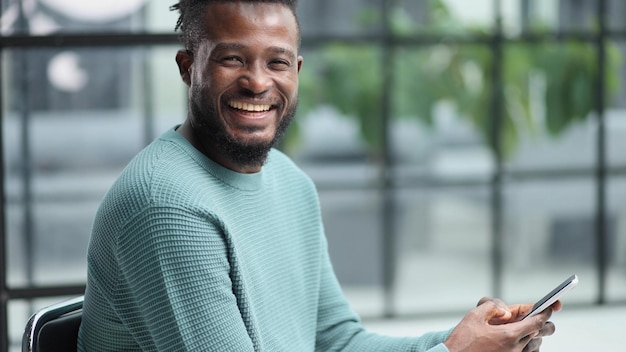 Afrikaans-Amerikaanse zakenman die op zijn werk telefoon, mobiele app's en sms'en gebruikt.