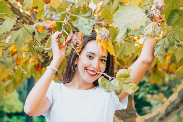 Afrikaans Arabisch jong meisje tussen gele bladeren glimlachend en groetend naar de camera. Natuurlijk geïsoleerd. Sociale netwerkdag bij aardconcept. Schoonheid portret. Ruimte voor tekst kopiëren en toevoegen. Gezondheid.