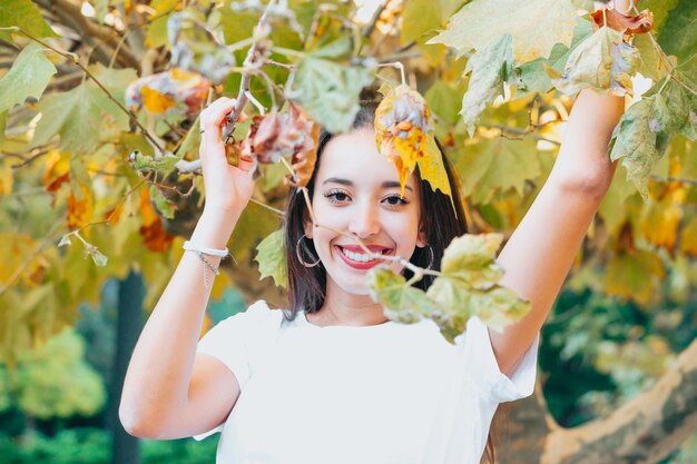 Afrikaans Arabisch jong meisje tussen gele bladeren glimlachend en groetend naar de camera. Natuurlijk geïsoleerd. Sociale netwerkdag bij aardconcept. Schoonheid portret. Ruimte voor tekst kopiëren en toevoegen. Gezondheid.