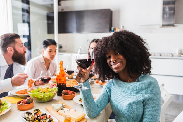 Afrikaans meisje met afrohaar dat een toast voorstelt tijdens een lunch