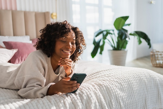 Afrikaans meisje met een smartphone touchscreen die thuis een pagina schrijft vrouw met een mobiele telefoon