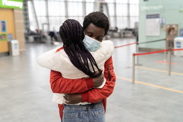 Afrikaans stel draagt gezichtsmaskers en knuffelt elkaar op luchthaventerminal