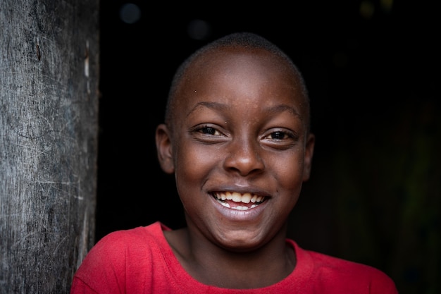 Afrikaans zwart jongensportret dat alleen in de buurt van zijn arme huis staat