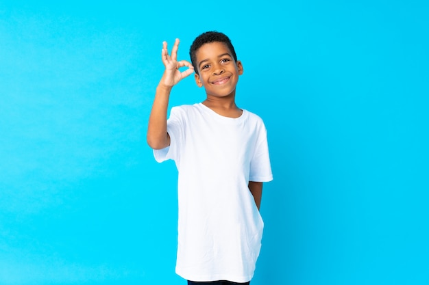Afrikaanse Amerikaanse jongen over blauw die ok teken met vingers tonen