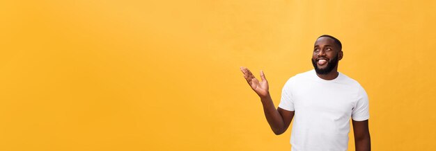 Afrikaanse Amerikaanse mens met baard die hand weg kant toont die over gele achtergrond wordt geïsoleerd