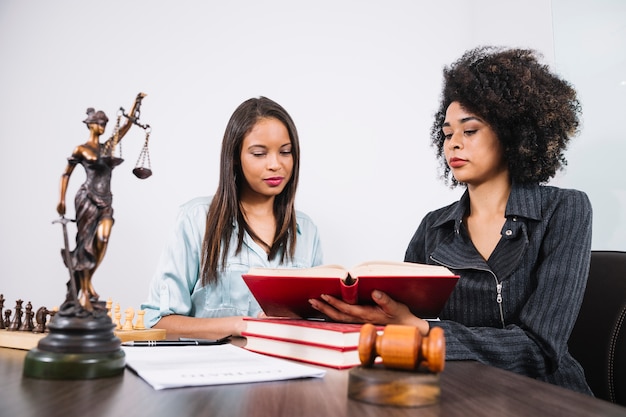 Afrikaanse Amerikaanse vrouw die boek tonen aan dame bij lijst met document, standbeeld en schaak