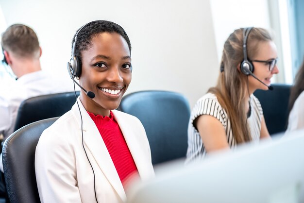 Afrikaanse Amerikaanse vrouw die in call centrebureau werkt met divers team