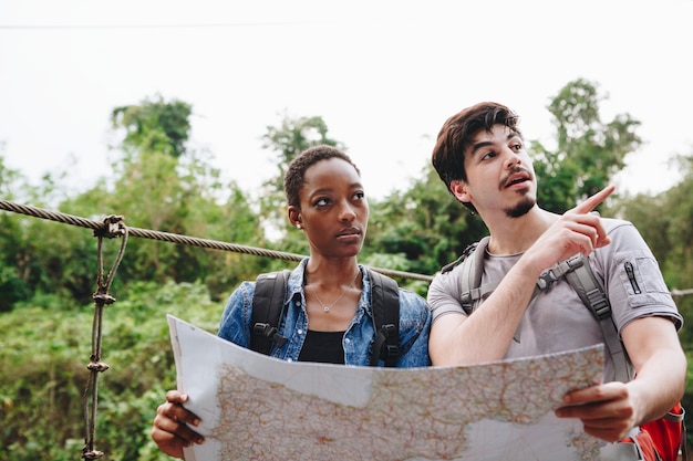 Afrikaanse Amerikaanse vrouw en een Kaukasische mens die een kaart samen reis en groepswerkconcept bekijken