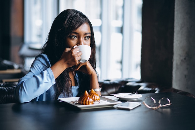 Afrikaanse Amerikaanse vrouw in een koffie die dessert eet