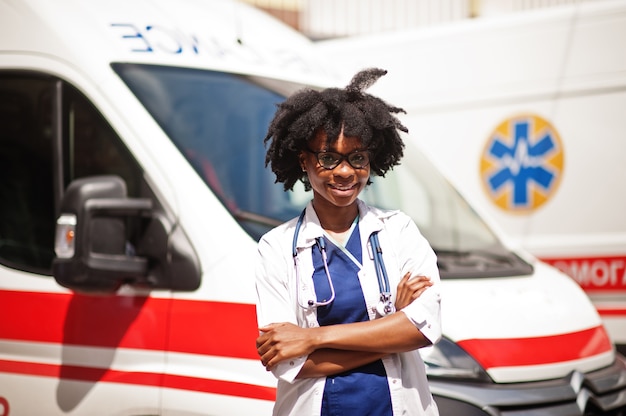 Afrikaanse Amerikaanse vrouwelijke paramedicus die zich voor ambulanceauto bevindt