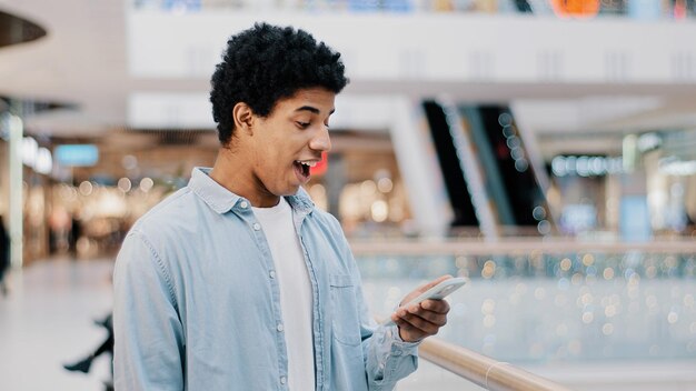 Afrikaanse Dominicaanse man verrast met telefoonnummer rinkelen kijken naar het scherm man beantwoorden onverwachte oproep praten glimlachen gelukkig praten mobiele vriendelijk casual praten met goed nieuws aanbod