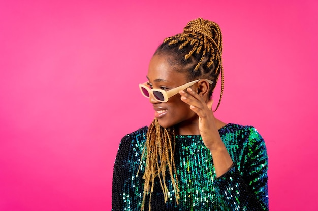 Afrikaanse jonge vrouw met partijvlechten op een roze achtergrondstudioportret met glazen