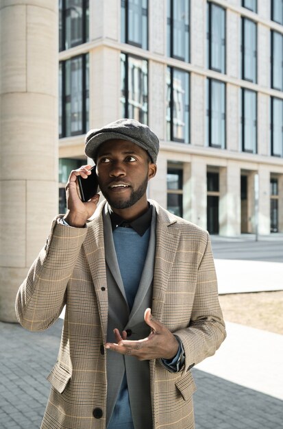 Afrikaanse jonge zakenman die op mobiele telefoon praat terwijl hij in de stad staat