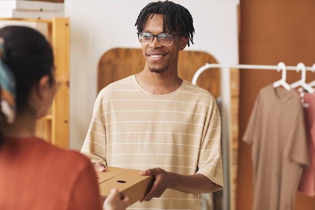 Afrikaanse jongeman die het pakket aan de vrouw geeft en zij het aflevert bij de klant