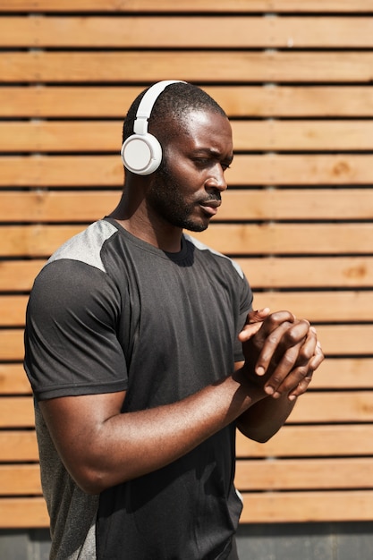 Afrikaanse jongeman in draadloze koptelefoon sloot zijn ogen en mediteerde terwijl hij buiten naar rustige muziek luisterde