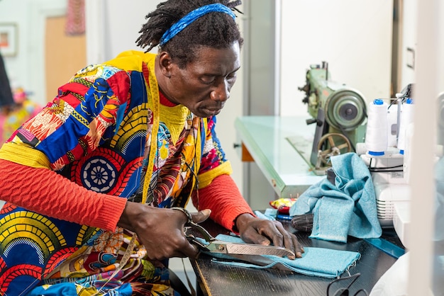 Afrikaanse kleermaker uit senegal aan het werk in zijn atelier handgemaakte productie van europese modekleding met afrikaanse waxstoffen concept van diversiteit en integratie nieuwe kleine sociale onderneming