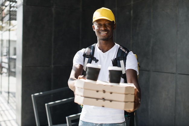 Afrikaanse koerier bezorgt dozen met pizza en warme koffie