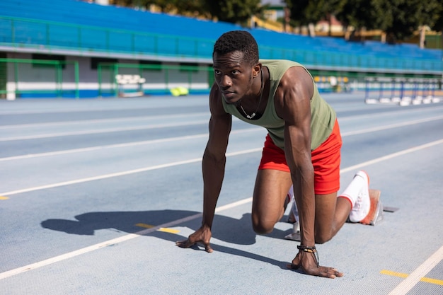 Afrikaanse loper in startpositie op atletiekbaan