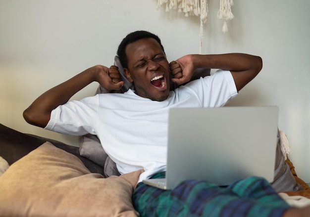 Afrikaanse man aan het werk liggend op bed thuis moe geeuwen