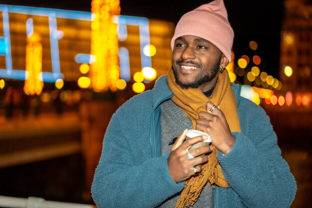 Afrikaanse man met koffie tijdens kerstnacht in de stad