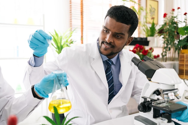 Afrikaanse man wetenschapper onderzoeker gebruikt een laboratoriumdruppelaar om een substantie in een erlenmeyer te druppelen voor analyse van vloeistoffen in het laboratorium Wetenschapper die werkt met een druppelaar en een erlenmeyer