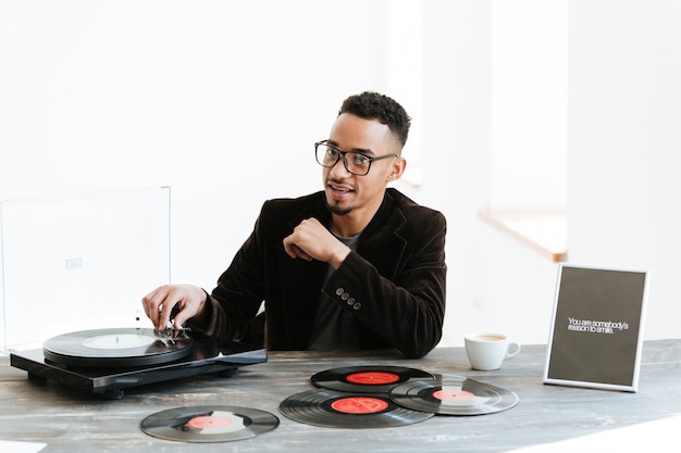 Afrikaanse man zit bij de tafel met platenspeler