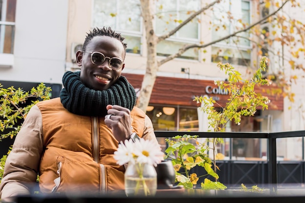 Afrikaanse man zit buiten trots met gebalde vuist glimlachend kijkend naar camera vooraanzicht portret