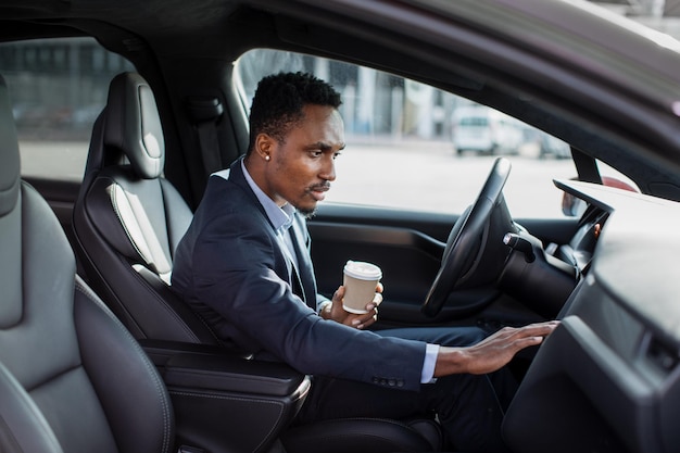 Foto afrikaanse man zit in moderne auto en gebruikt dashboard