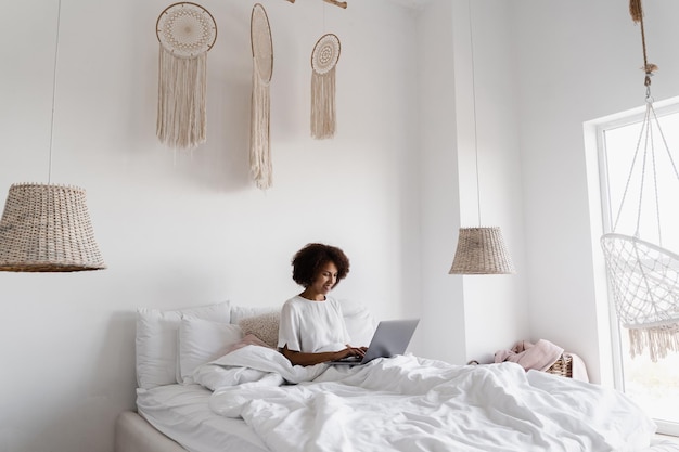Afrikaanse meisjesmanager met laptop heeft 's ochtends online videovergadering met collega's en zakenpartners in een gezellig bed thuis Teamdiscussietrends en -taken