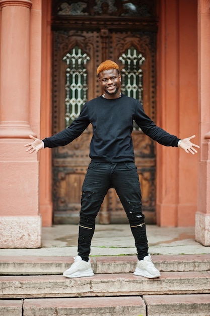 Afrikaanse roodharige man draagt een zwarte outfit die buiten poseert.