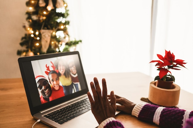 Afrikaanse senior vrouw doet videogesprek met haar familie tijdens de kerstperiode - focus op linkerhand