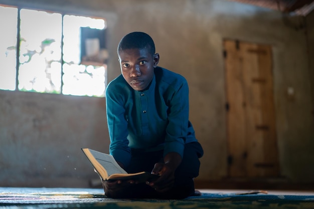 Afrikaanse tiener zit en leest een boek op een arme school, foto van hoge kwaliteit