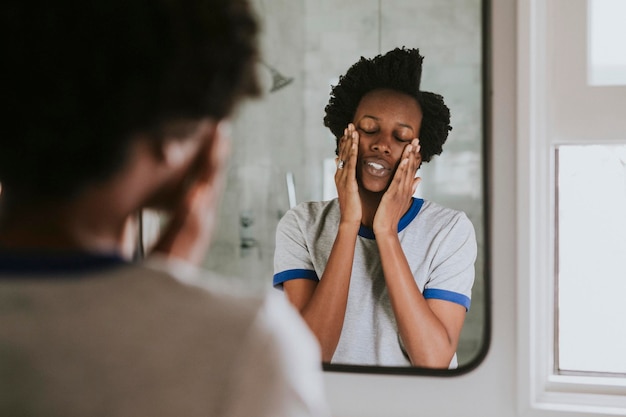 Afrikaanse vrouw die bij de spiegel in de badkamer staat