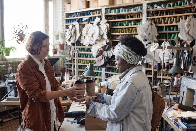 Afrikaanse vrouw die een kopje koffie brengt voor haar collega tijdens de koffiepauze in de werkplaats