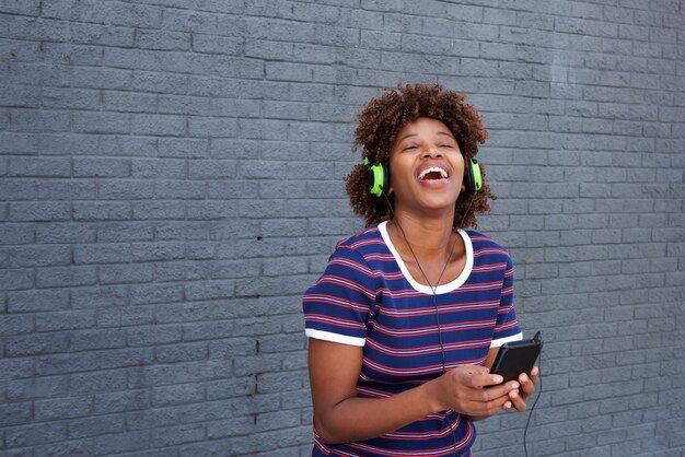 Afrikaanse vrouw die van muziek met hoofdtelefoons en mobiele telefoon geniet