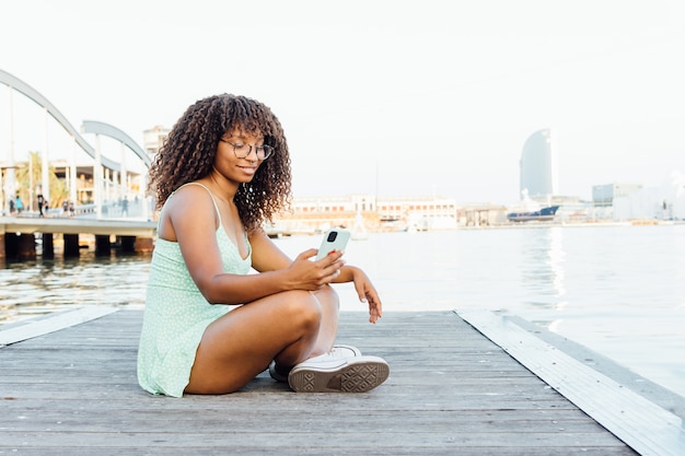 Afrikaanse vrouw met behulp van haar smartphone aan zee