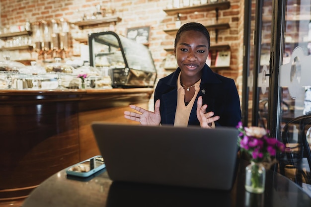 Afrikaanse vrouw met een videogesprek op laptop terwijl ze in café zit