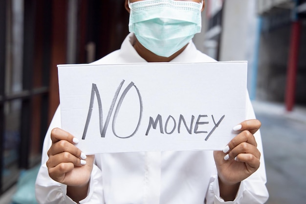 Afrikaanse vrouw met gezichtsmasker die geen geld heeft als gevolg van de onderbreking van de werkgelegenheid na de pandemie van COVID19 die leidde tot een economische recessie
