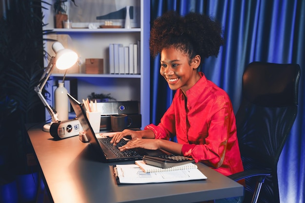 Afrikaanse vrouwelijke blogger met een roze shirt met een gelukkig gezicht die op het scherm kijkt laptop met gewaardeerde prestatie project of krijg een beurs Concept van vrolijke expressie werk vanuit huis Tastemaker