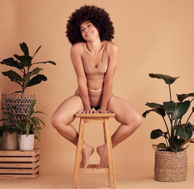 Afrikaanse vrouwenlingerie en studio met glimlachkruk en planten voor ondergoed van natuurlijk materiaal Zwarte vrouw gelukkige en duurzame katoenen stof met bladeren zelfliefde en schoonheid door beige achtergrond
