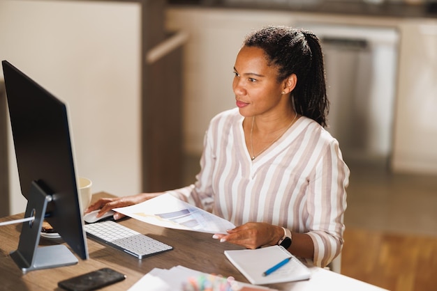 Afrikaanse zakenvrouw die op de computer werkt vanuit haar thuiskantoor.