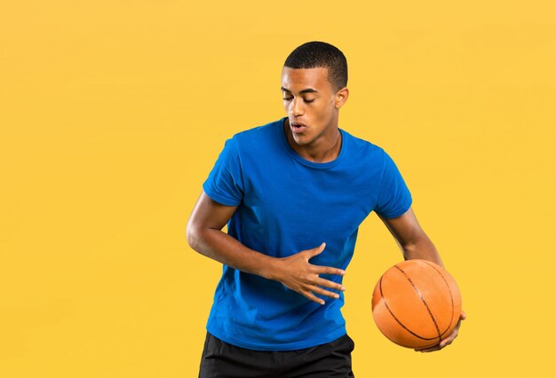 Afro american basketball player man over isolated yellow\
wall