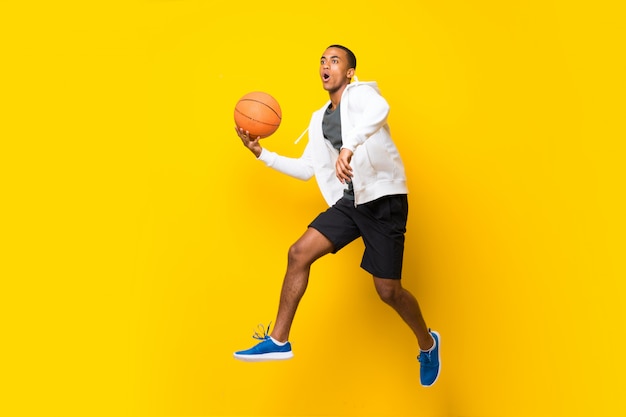 Afro American basketball player man over isolated yellow wall