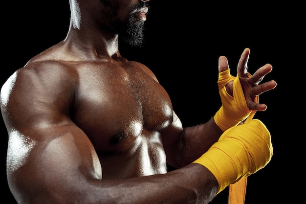 Afro American boxer is wrapping hands with yellow bandage