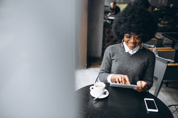 Photo afro american business woman with tablet and coffee in a cafe