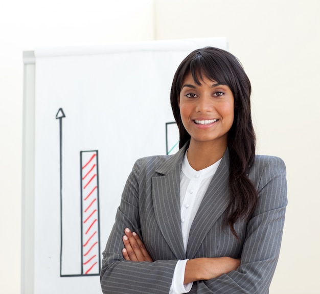 Afro-american businesswoman with folded arms in front of a board 