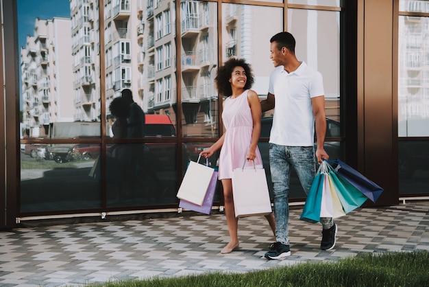 アフリカ系アメリカ人のカップルは買い物袋を持って歩いています
