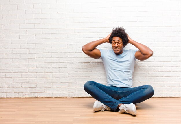 an afro-american guy sitting with hands on head panicking at mistake