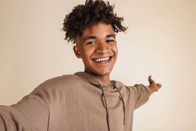 Photo afro american man dressed in hoodie taking a selfie isolated.