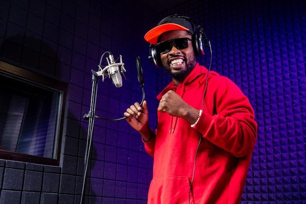 afro american man headphones in a cap and a hood sunglasses recording hip hop song track.